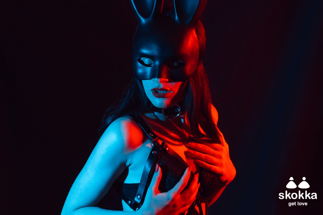 An image of a dominatrix escort dressed in a bondage mask and lingerie.