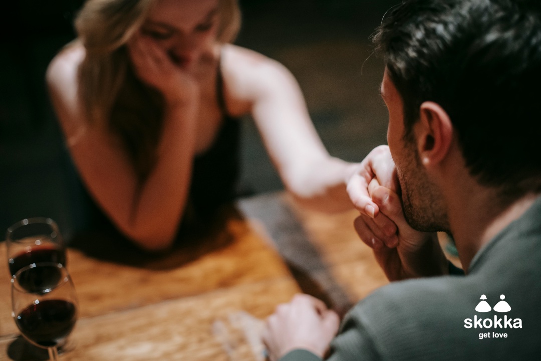 Una imagen de un hombre en una cita, besando la mano de una escort en un restaurante para representar consejos de citas para hombres.